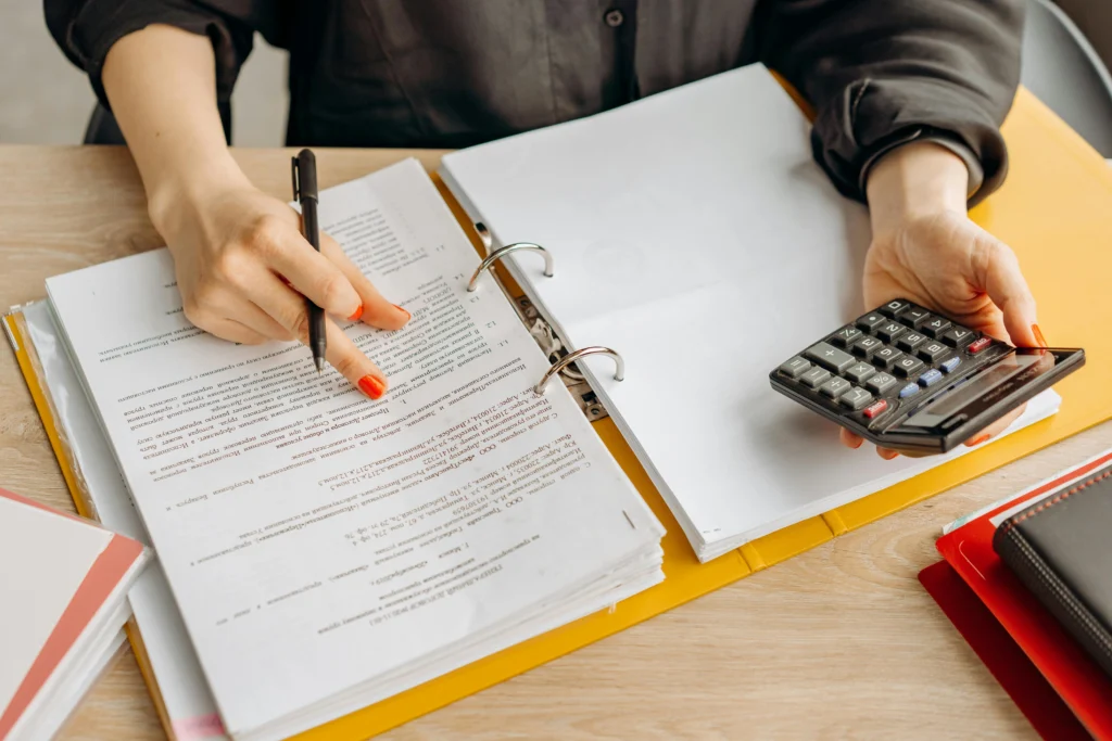 Senior accountant reviewing financial documents with a calculator at a small CPA firm